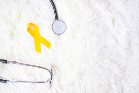Yellow Ribbon and Stethoscope on white background for supporting people living and illness. September Suicide prevention day, Childhood Cancer Awareness month and World cancer day conceptの写真素材