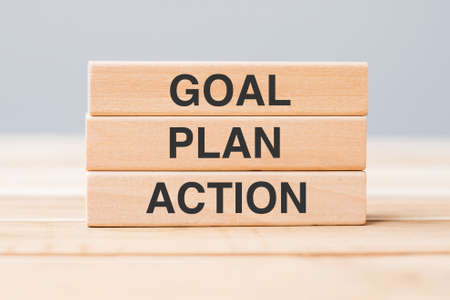 wooden block with GOAL, PLAN and ACTION on table backgroundの写真素材