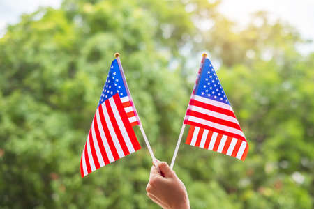 hand holding United States of America flag on green background. USA holiday of Veterans, Memorial, Independence ( Fourth of July) and Labor Day conceptの写真素材
