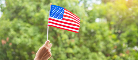 hand holding United States of America flag on green background. USA holiday of Veterans, Memorial,...
