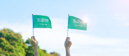 hand holding Saudi Arabia flag on blue sky background. September Saudi Arabia national day and Happy celebration conceptsの写真素材