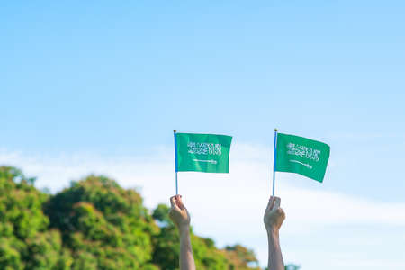 hand holding Saudi Arabia flag on blue sky background. September Saudi Arabia national day and Happy celebration conceptsの写真素材