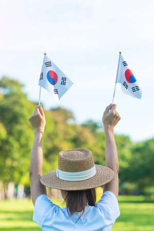 Woman hand holding Korea flag on nature background. National Foundation, Gaecheonjeol, public Nation holiday, National Liberation Day of Korea and happy celebration conceptsの写真素材