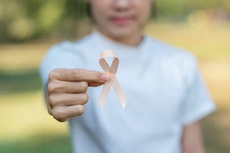 September Uterine Cancer Awareness month, woman hand holding Peach Ribbon for supporting people living and illness. Healthcare and World cancer day conceptの写真素材