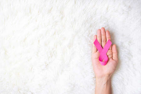October Breast Cancer Awareness month, adult Woman  hand holding Pink Ribbon on pink background for supporting people living and illness. International Women, Mother and World cancer day conceptの写真素材