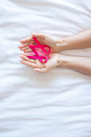 October Breast Cancer Awareness month, adult Woman  hand holding Pink Ribbon on pink background for supporting people living and illness. International Women, Mother and World cancer day conceptの写真素材