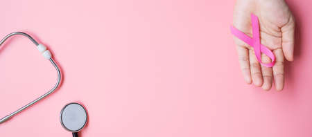 Breast Cancer Awareness, woman holding Pink Ribbon with Stethoscope on pink background for...