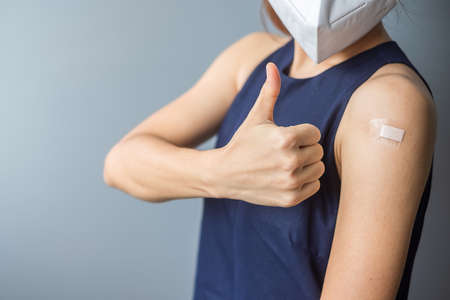 woman showing her arm with bandage after receiving   vaccine. Vaccination, herd immunity, side effect, vaccine efficiency and virus pandemicの写真素材