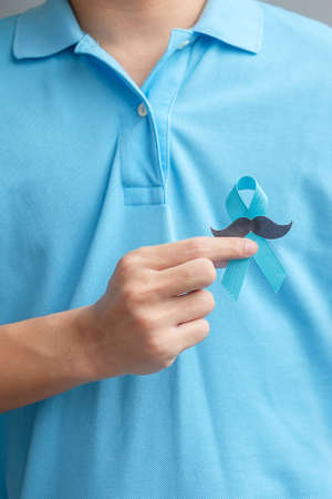 November Prostate Cancer Awareness month, Man holding Blue Ribbon with mustache for supporting...