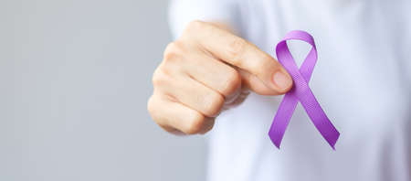 Hand holding purple Ribbon for Pancreatic, Esophageal, Testicular cancer, world Alzheimer, epilepsy,...