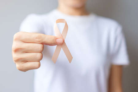 woman hand holding Peach Ribbon for September Uterine Cancer Awareness month. Healthcare and World...