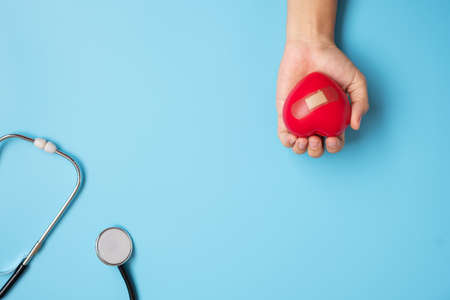 Doctor hand holding Red heart shape with Stethoscope on blue background. Healthcare, life Insurance...