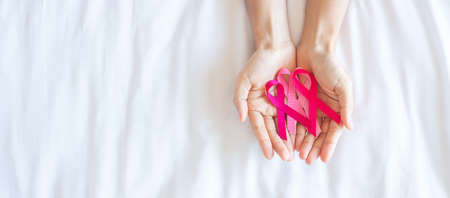 October Breast Cancer Awareness month, adult Woman  hand holding Pink Ribbon on pink background for supporting people living and illness. International Women, Mother and World cancer day conceptの写真素材