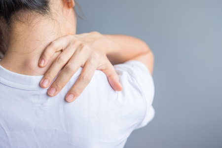 woman with her shoulder sprain, muscle painful during overwork. Girl having body problem after wake up. Shoulder ache, Scapular pain, office syndrome and ergonomic conceptの写真素材