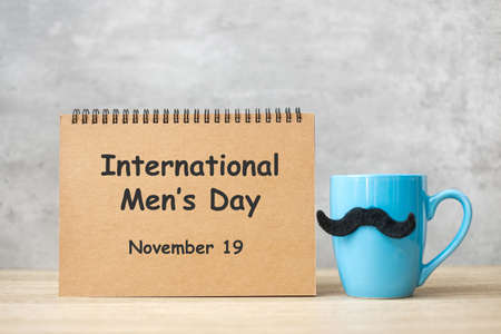 International Men day with paper notepad, Blue coffee cup or tea mug and Black mustache decor on...