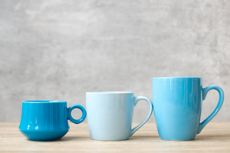 Blue coffee cup and tea mug on wood table background in the morning, Blank copy space for text. International coffee day and daily routine conceptの写真素材