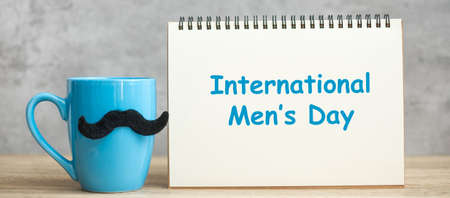 International Men day with paper notepad, Blue coffee cup or tea mug and Black mustache decor on table. Happy father day and celebration conceptの写真素材