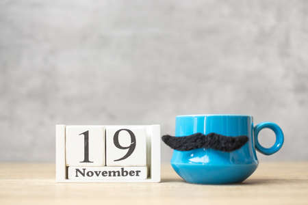International Men day with November 19 calendar, Blue coffee cup or tea mug and Black mustache decor on table. Happy father day and celebration conceptの写真素材