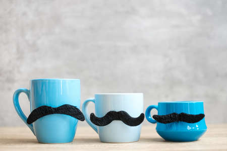 Blue coffee cup and tea mug with Black mustache decor on wood table background in the morning. Blue November, Happy Father day and International men day conceptの写真素材