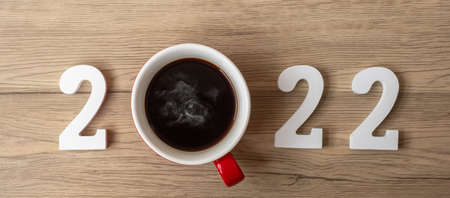 2022 Happy New Year with coffee cup and Christmas decoration on wood table background. New Start,...