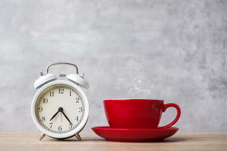 Hot espresso coffee and vintage clock on table, Red coffee cup in cafe or home in the morning....