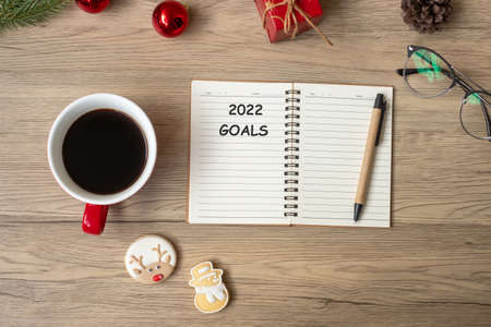 2022 GOAL with notebook, black coffee cup, Christmas cookies and pen on wood table. Xmas, Happy New Year, Resolution, To do list, Strategy and Plan conceptの写真素材