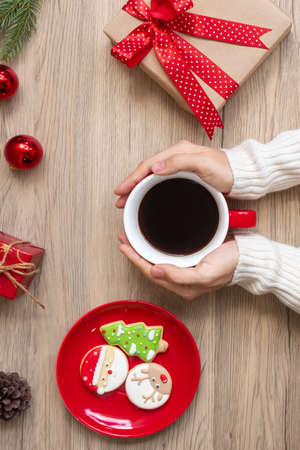 Merry Christmas with woman hand holding coffee cup and homemade cookie on table. Xmas eve, party, holiday and happy New Year conceptの写真素材
