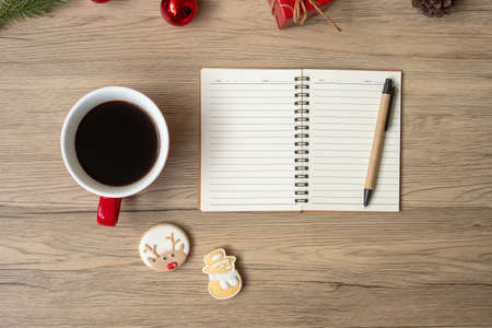 Blank notebook, black coffee cup, Christmas cookies and pen on wood table, Top view and copy space. Xmas, Happy New Year, Goals, Resolution, To do list, Strategy and Plan conceptの写真素材