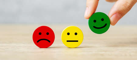 hand holding emotion face block. Customer choose Emoticon for user reviews. Service rating, ranking, customer review, satisfaction, mood, evaluation and feedback conceptの写真素材