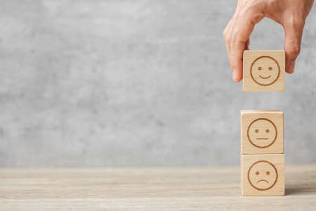 hand holding emotion face block. Customer choose Emoticon for user reviews. Service rating, ranking,...