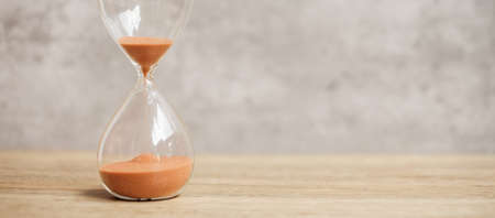 Hourglass on table, Sand flowing through the bulb of Sandglass measuring the passing time. countdown, deadline, Life time and Retirement conceptの写真素材