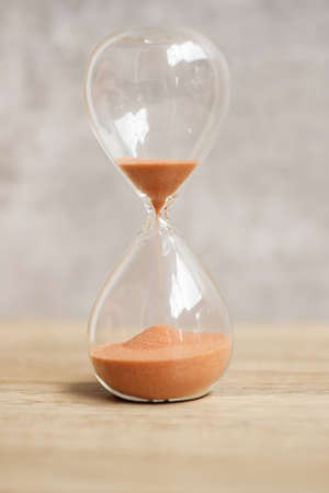 Hourglass on table, Sand flowing through the bulb of Sandglass measuring the passing time. countdown, deadline, Life time and Retirement conceptの写真素材