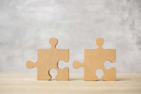 connecting couple puzzle piece, wood jigsaw on table. Business solutions, mission, success, goals and strategy conceptsの写真素材