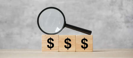 American Dollar symbol block with hand holding glass magnifying. Money, cash, currency and investment concept.の写真素材