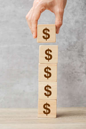 Businessman hand holding wooden blocks with the American Dollar symbol. Money, cash, currency and investment concept.の写真素材