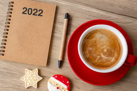 2022 GOAL with notebook, coffee cup, Christmas cookies and pen on wood table. Xmas, Happy New Year, Resolution, To do list, Strategy and Plan conceptの写真素材