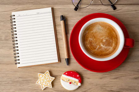 Blank notebook, black coffee cup, Christmas cookies and pen on wood table, Top view and copy space. Xmas, Happy New Year, Goals, Resolution, To do list, Strategy and Plan conceptの写真素材