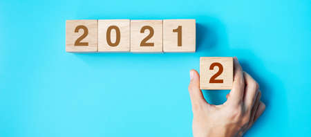 hand holding wooden cube block with 2022 text on blue background. Resolution, plan, review, goal, start and New Year holiday conceptsの写真素材