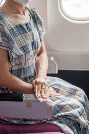 woman clean seat by wet wipe tissue in airplane or public transportation. New Normal, safety and  personal hygiene conceptsの写真素材