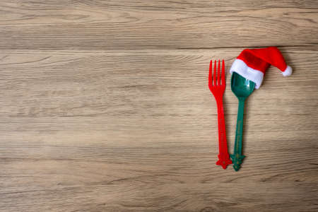 Merry Christmas with miniature Santa Claus, fork and spoon on wood table background. Xmas, party and happy New Year conceptの写真素材