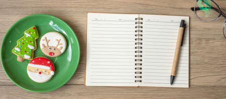 Blank notebook, black, Christmas cookies and pen on wood table, Top view and copy space. Xmas, Happy New Year, Goals, Resolution, To do list, Strategy and Plan conceptの写真素材