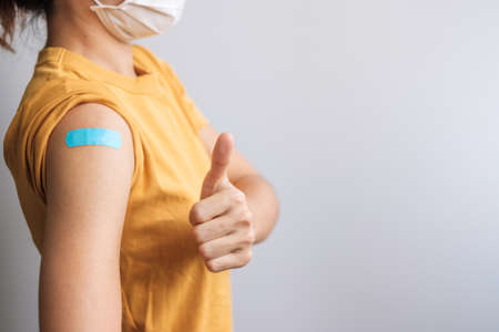 woman showing Thumb sign with bandage after receiving covid 19 vaccine. Vaccination, herd immunity, side effect, booster dose, vaccine passport and Coronavirus pandemicの写真素材