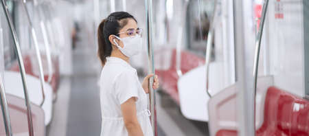 woman wearing Medical face mask and listening music by earphones in train. public transportation and...