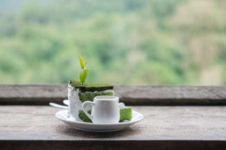 Green tea cake with young bud tea leaf on wooden table against tea garden backgroundの写真素材