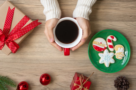 Merry Christmas with woman hand holding coffee cup and homemade cookie on table. Xmas eve, party, holiday and happy New Year conceptの写真素材