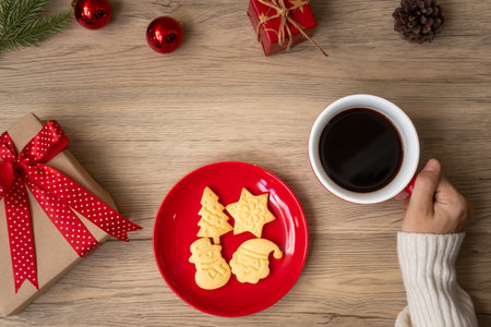 Merry Christmas with woman hand holding coffee cup and homemade cookie on table. Xmas eve, party, holiday and happy New Year conceptの写真素材