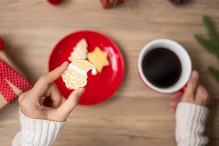 Merry Christmas with woman hand holding coffee cup and homemade cookie on table. Xmas eve, party, holiday and happy New Year conceptの写真素材