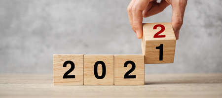 hand flipping block 2021 to 2022 text on table. Resolution, strategy, plan, goal, motivation, reboot, business and New Year holiday conceptsの写真素材