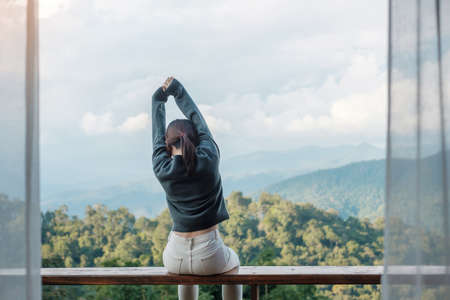 Happy woman relaxing and looking mountain view at countryside home or homestay in the morning. Vacation, blogger, SoloTravel, journey, trip and relaxing conceptの写真素材