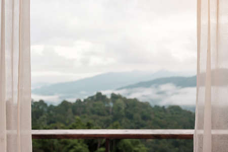 Beautiful mountain view with balcony and window curtain at countryside home or homestay in the morningの写真素材